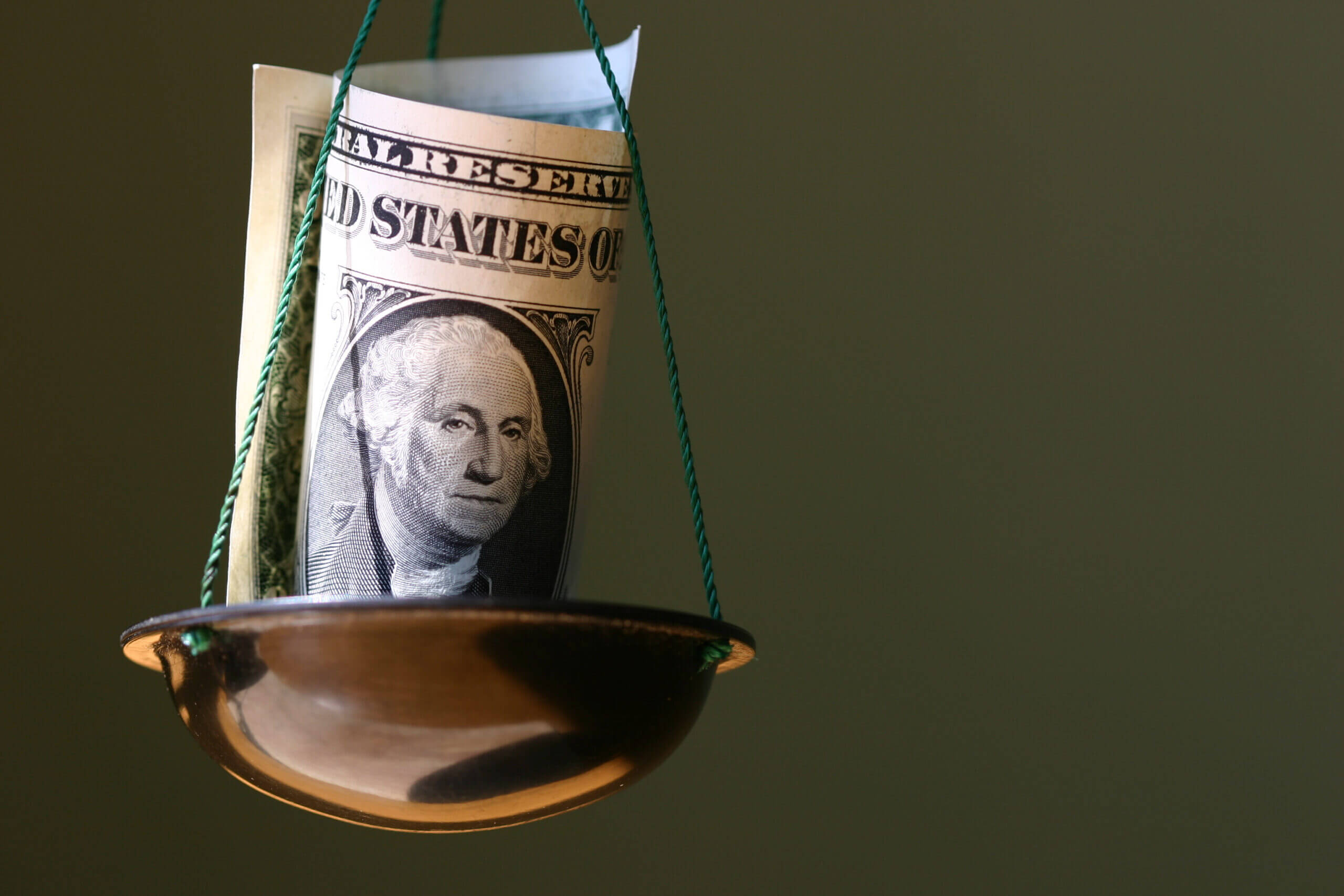 Dollar in a bowl of balance (Viktor_Kitaykin/E+ via Getty Images)