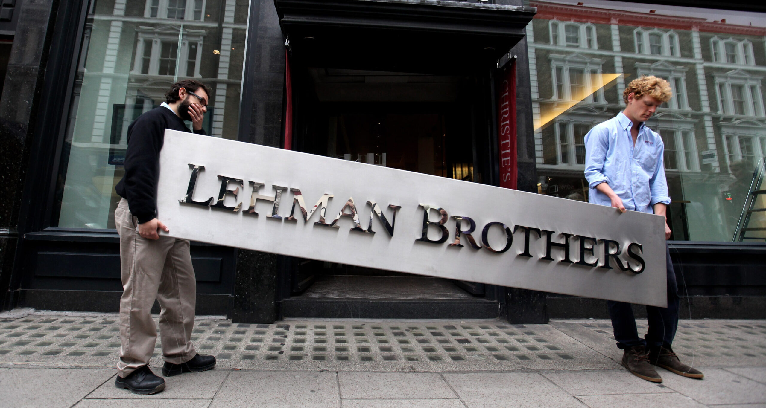 Two employees of Christie's auction house maneuver the Lehman Brothers corporate logo featured in the sale of the art owned by the collapsed investment bank (Oli Scarff/Getty Images)