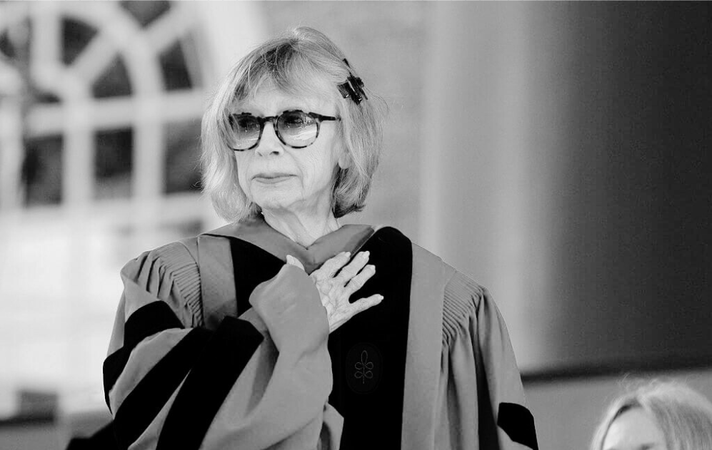 A woman stands in academic regalia