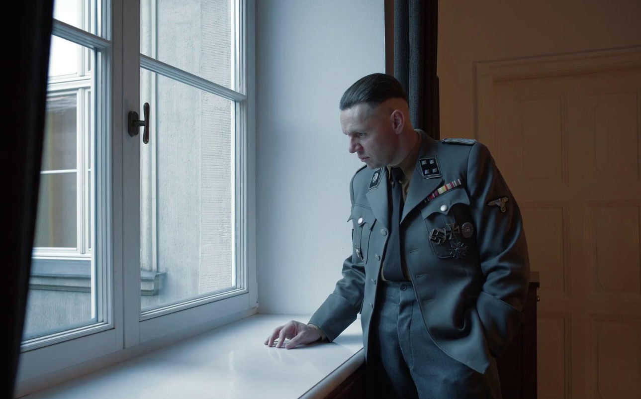 A man in uniform looks out a window