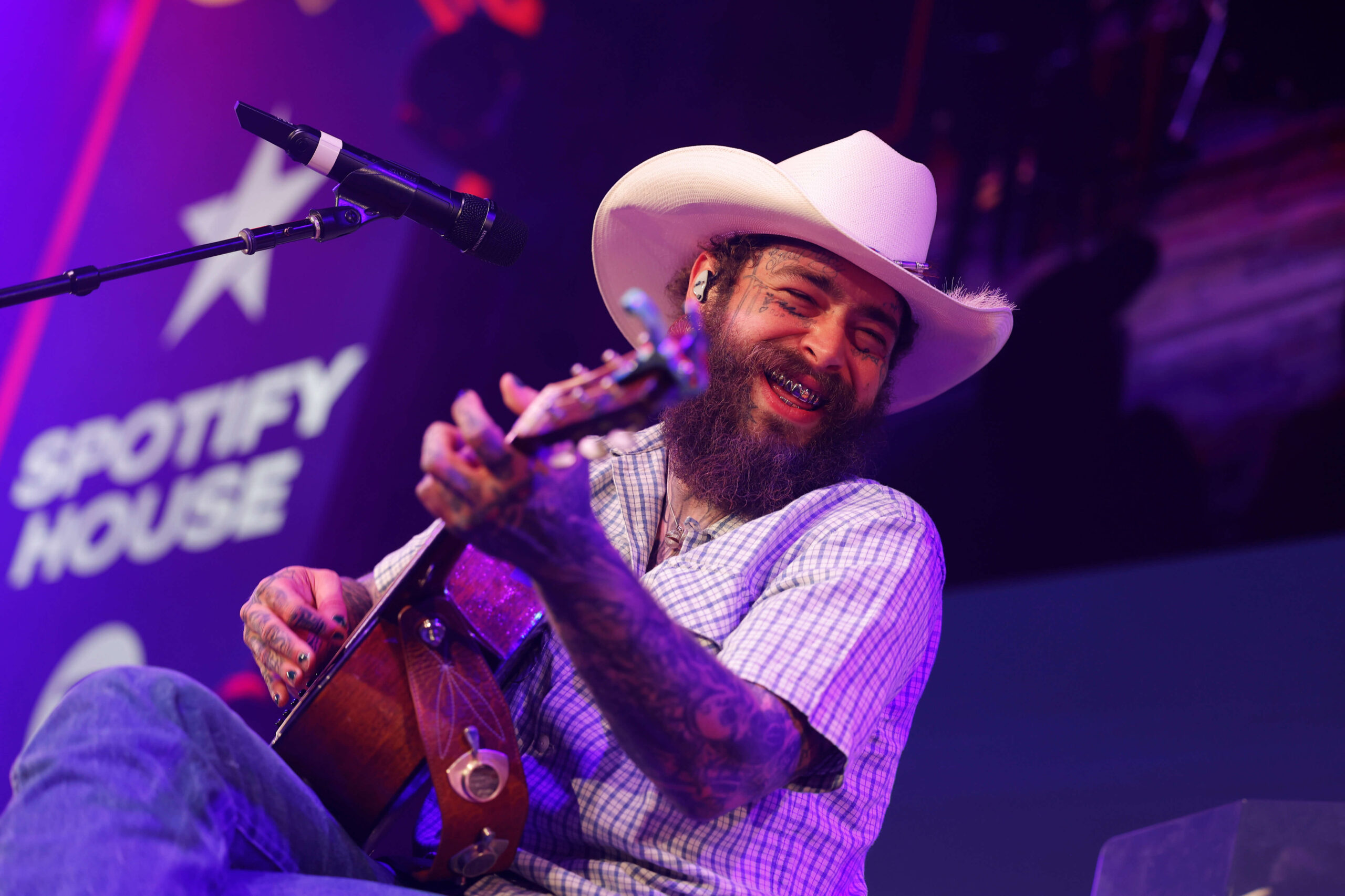 Post Malone plays guitar and wears a cowboy hat